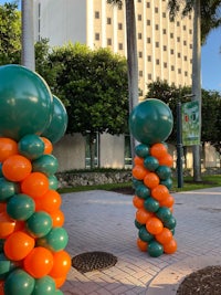 a group of orange and green balloons in front of a building