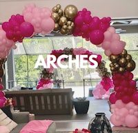 a pink and gold balloon arch in a living room