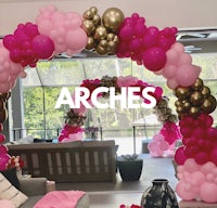 a pink and gold balloon arch in a living room