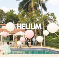 a group of people standing around a pool with balloons